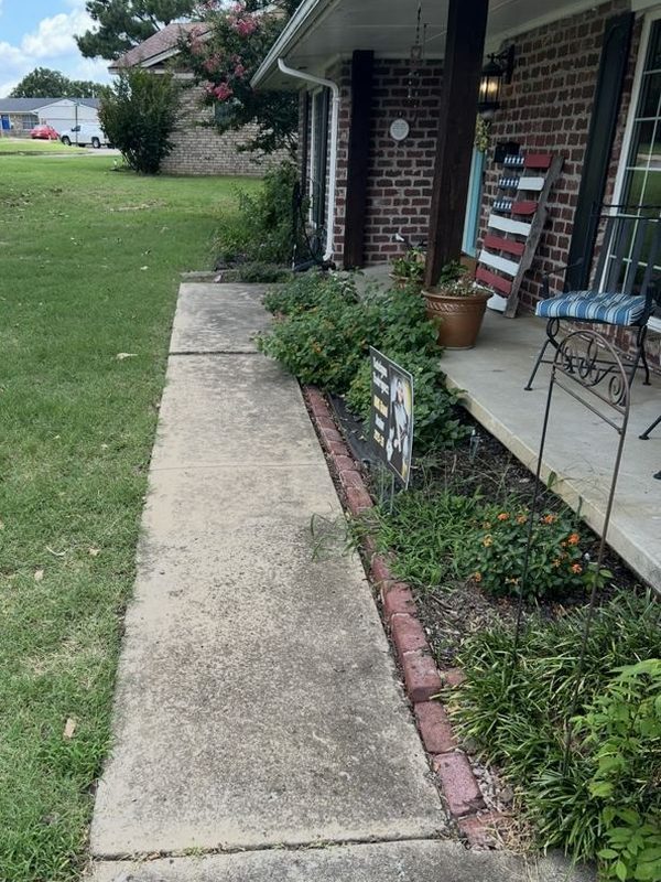 Concrete walkway at a brick home, stained and darkened, before cleaning